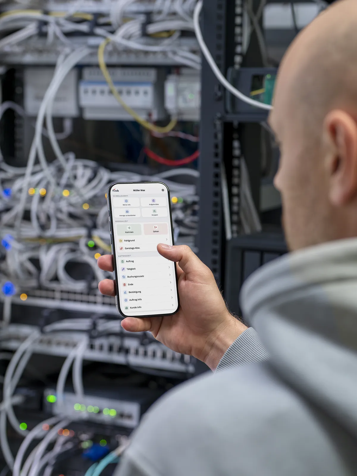 Techniker im Serverraum mit der Fink Mobilversion am Smartphone