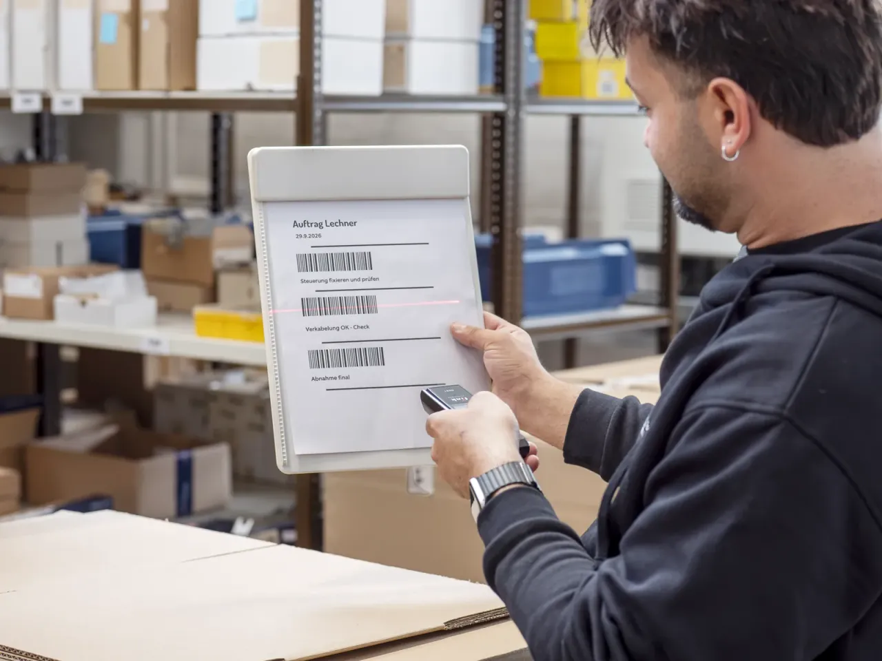 Mitarbeiter scannt den Barcode auf einem Auftragsblatt im Lager
