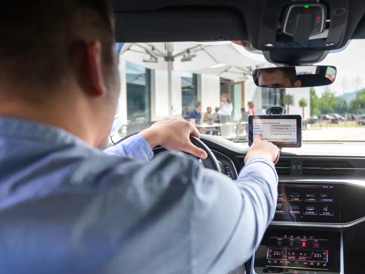 Fahrer bedient das Tablet im Firmenwagen