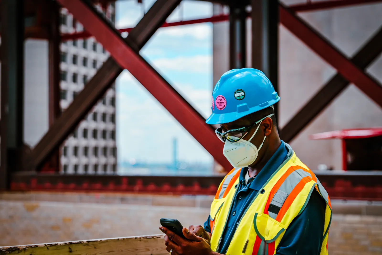 Bauarbeiter mit Helm bucht auf der Baustelle am Smartphone